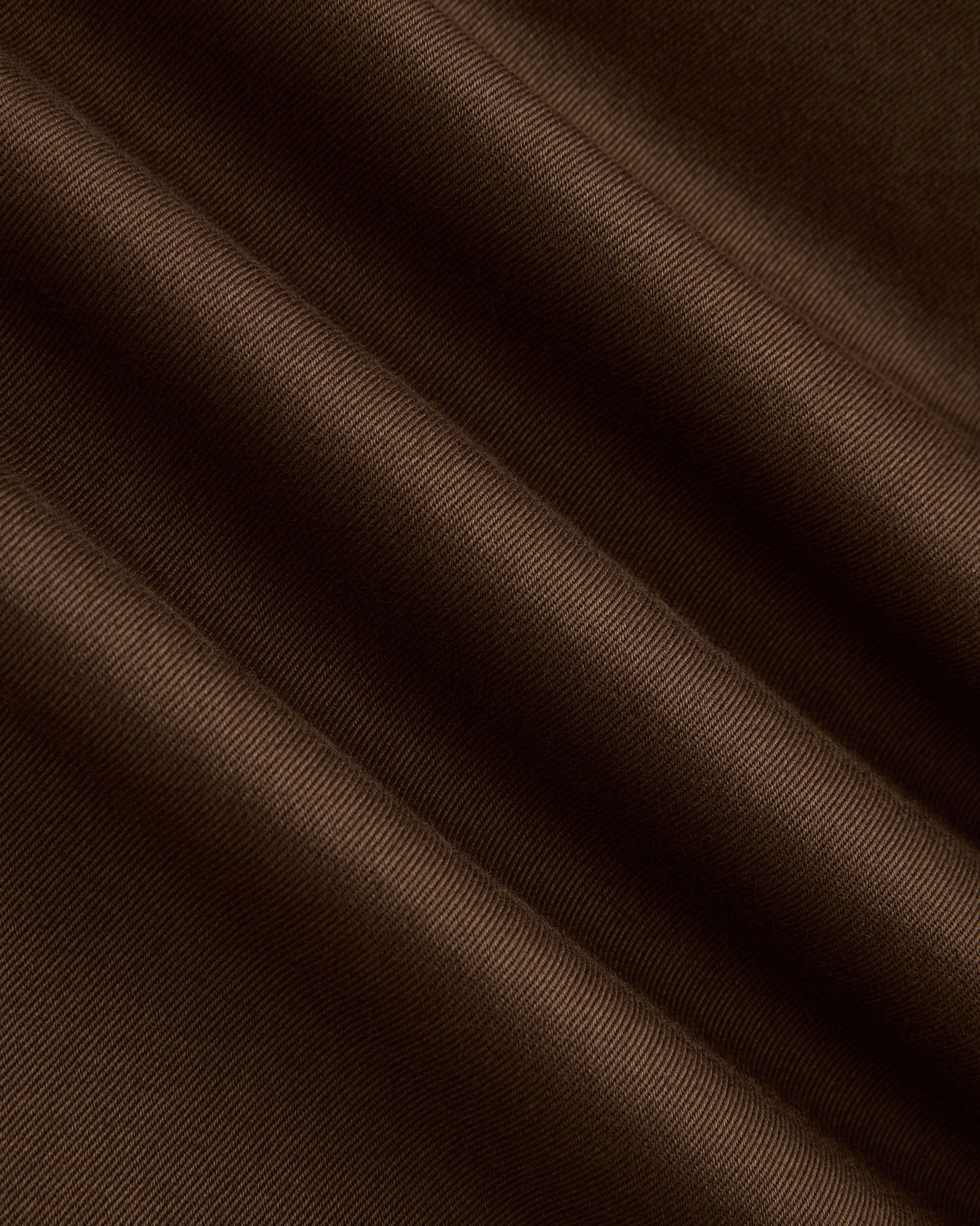 Close-up of brown ribbed fabric texture with diagonal folds and shadows